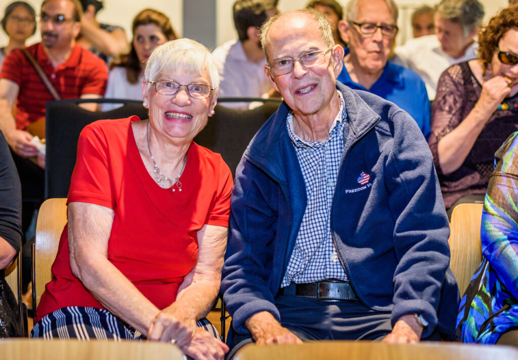 TWo older adults smile for the camera at a concert