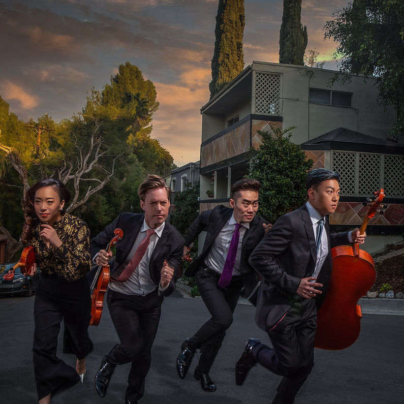 The Rolston String Quartet, running towards in the camera with their instruments in slightly different directions,