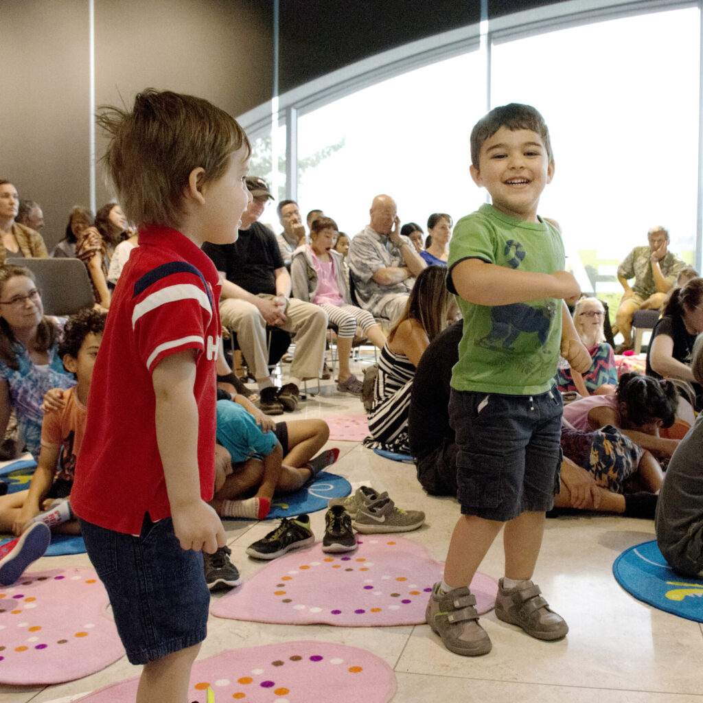 Two young audience members dance and smile at a Xenia Concert.