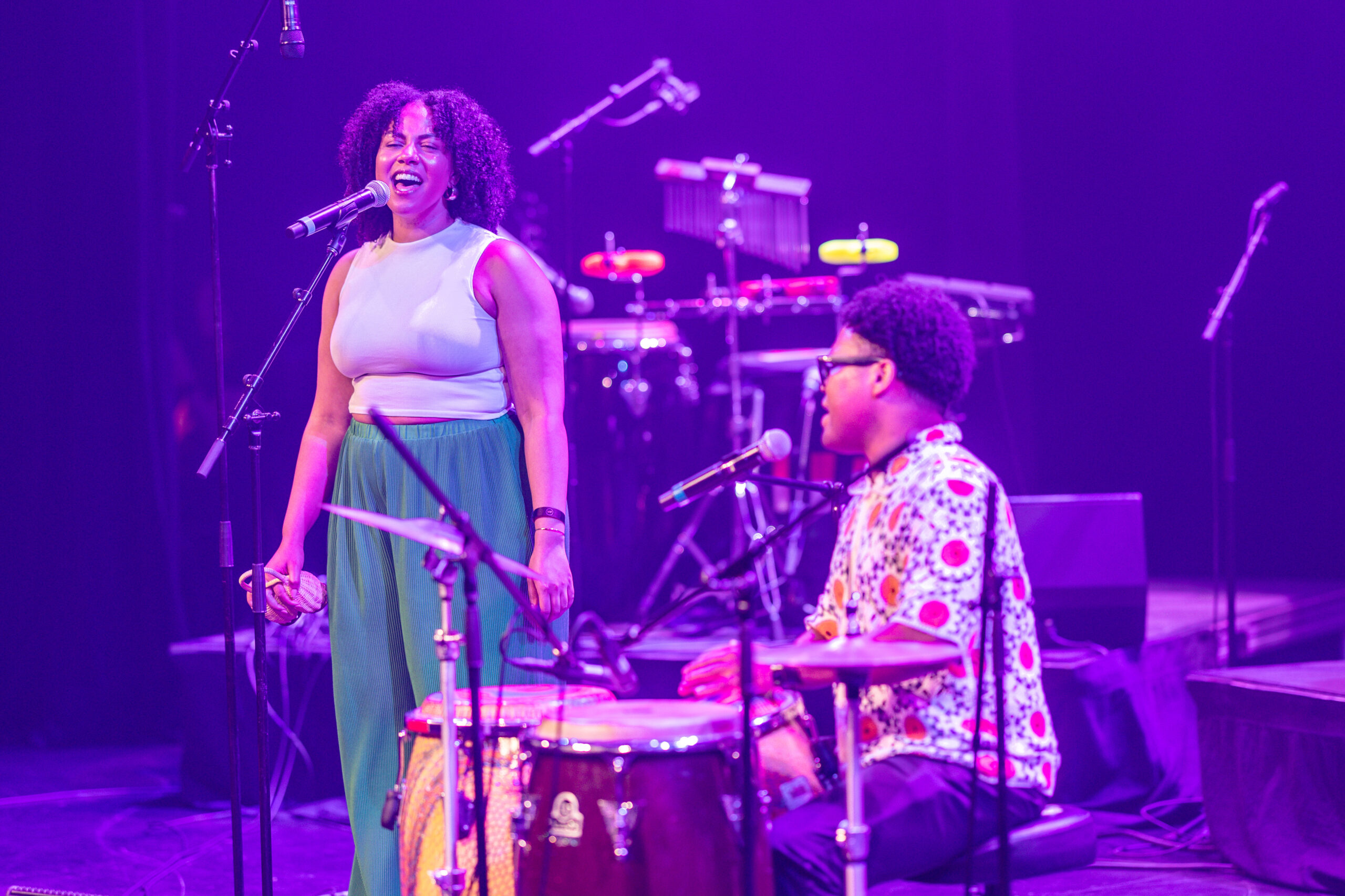 A singer and a percussionist perform together on stage