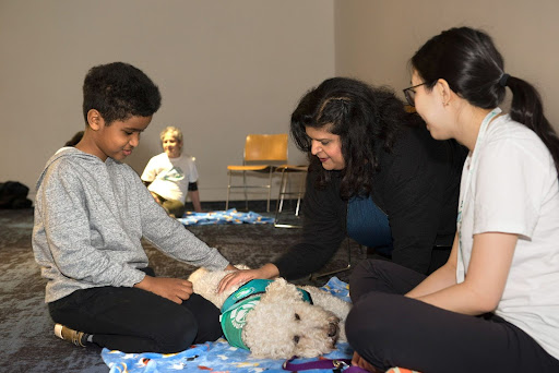 Two audience members, a mother and son, meet with one of One Health Partners' therapy dogs and their handler.