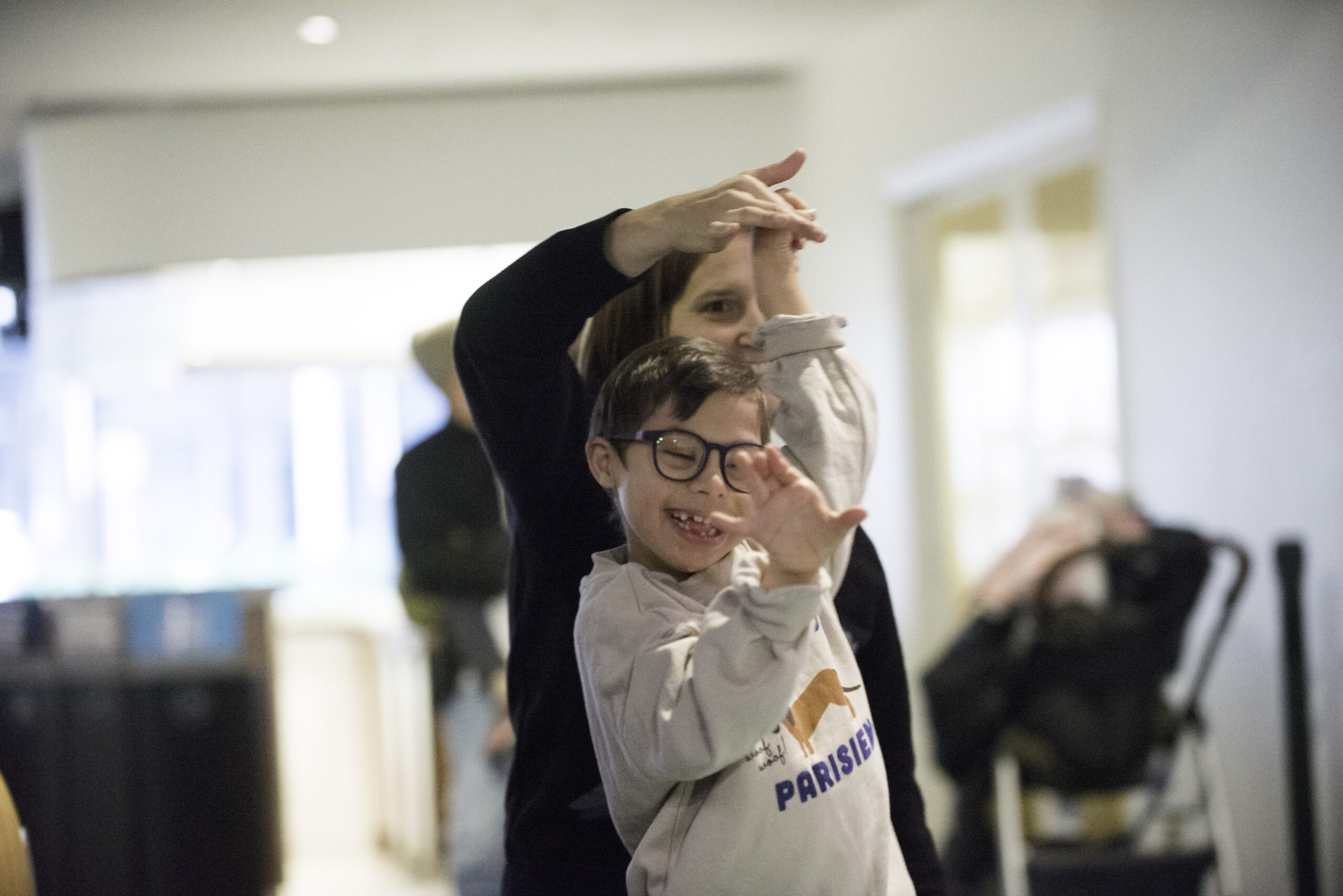 A child and an adult dance together while holding hands.